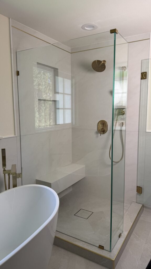 Finished frameless glass shower enclosure with brushed gold rain shower head and fixtures