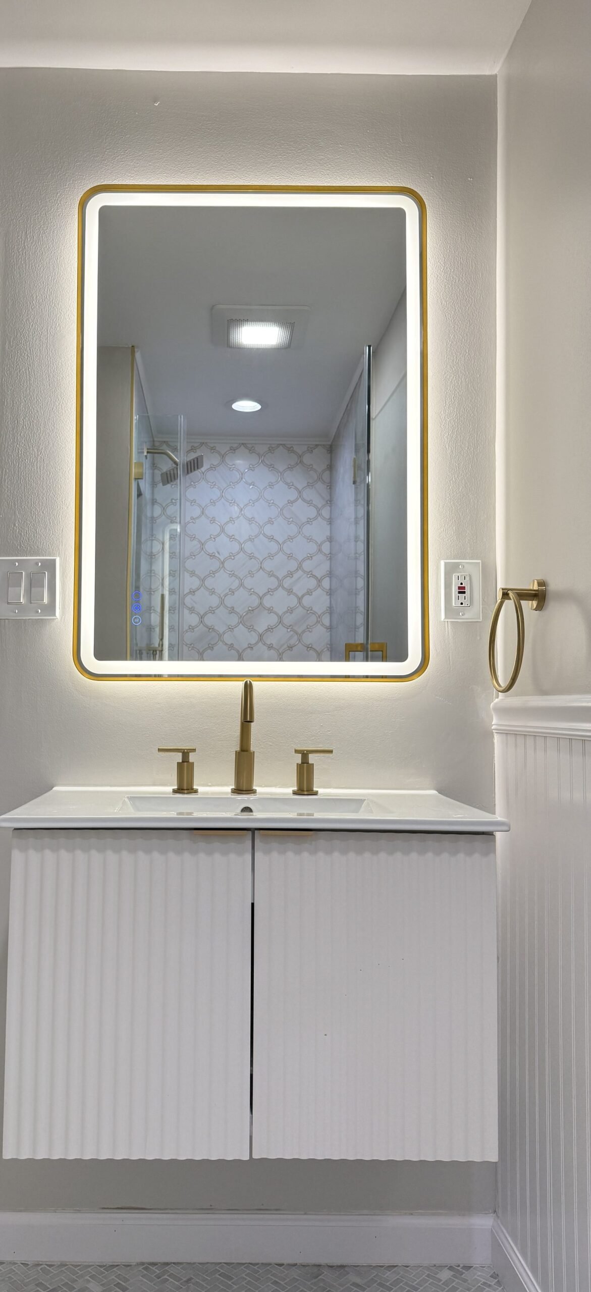 Bathroom vanity with backlit gold-framed LED mirror and brushed gold faucet