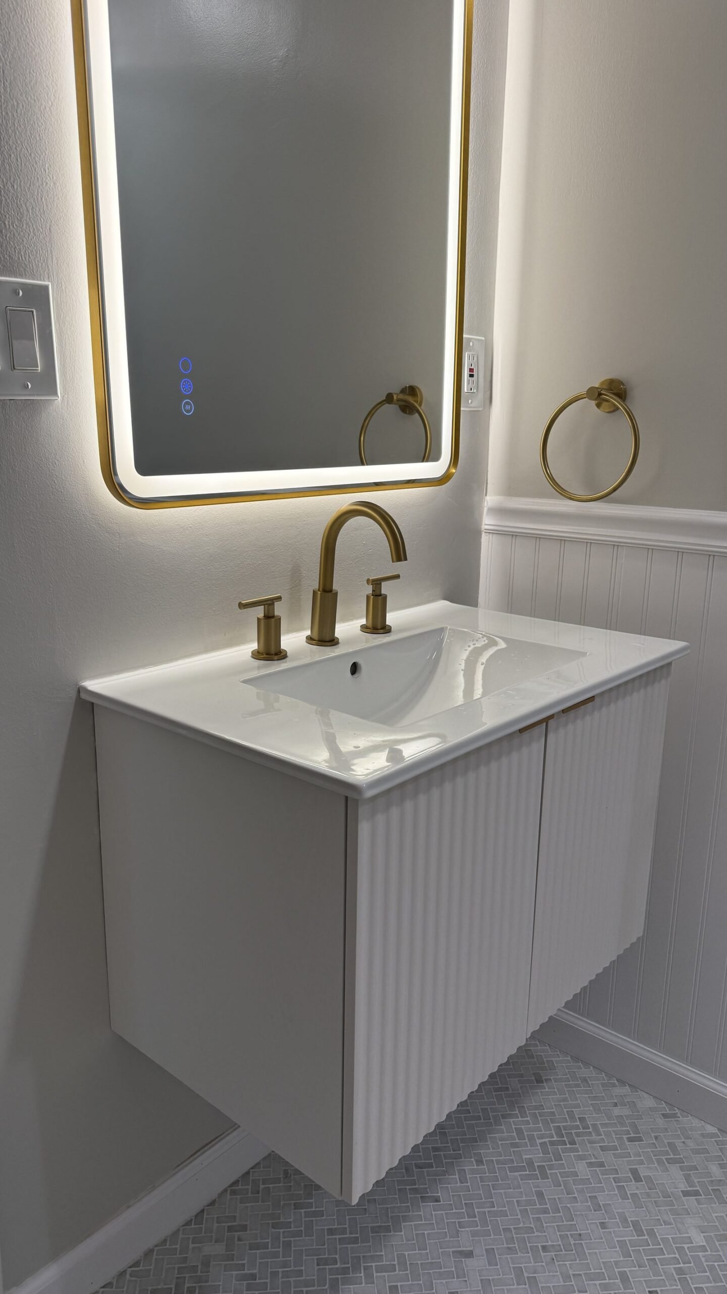 Close-up of the floating fluted vanity with brushed gold hardware and towel ring